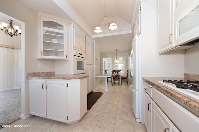 kitchen featuring pendant lighting, white cabinets, and white appliances