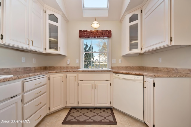 kitchen with sink, white cabinetry, a skylight, light tile patterned floors, and white dishwasher