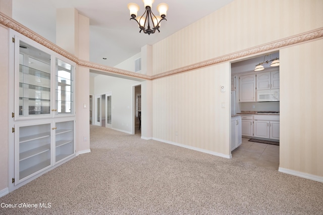 unfurnished room featuring light carpet, a notable chandelier, and high vaulted ceiling