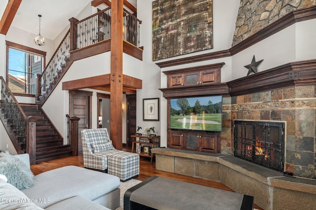 living room with a fireplace, a towering ceiling, wood-type flooring, and a chandelier