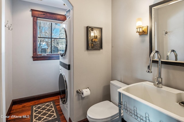 bathroom with wood-type flooring, stacked washer / drying machine, sink, and toilet