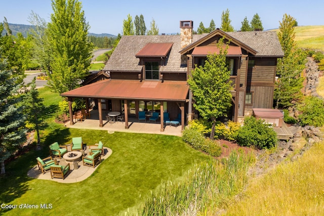 rear view of house with a patio, a yard, and an outdoor living space with a fire pit