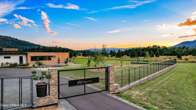 gate at dusk featuring a mountain view, a yard, and a rural view