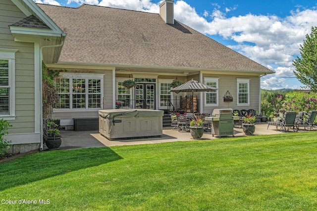 back of house featuring a yard, a hot tub, and a patio area