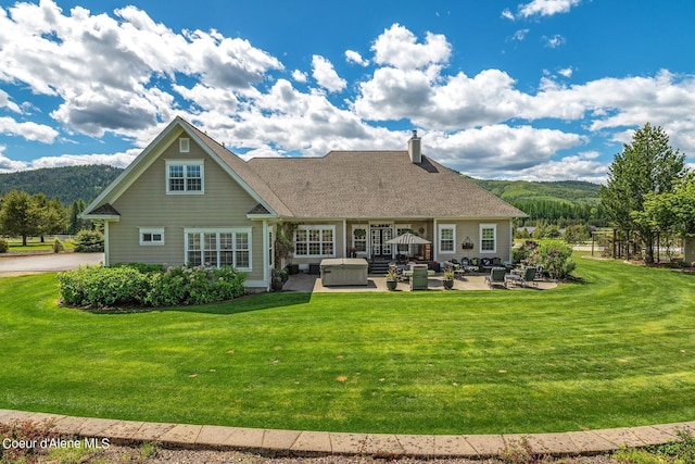 back of house with a mountain view, a lawn, a hot tub, and a patio