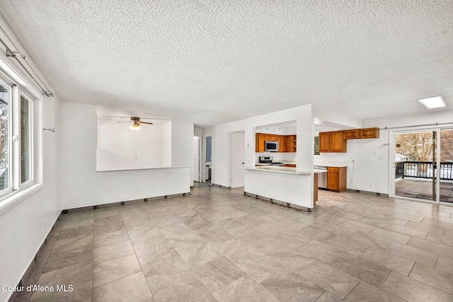 unfurnished living room with ceiling fan and a textured ceiling