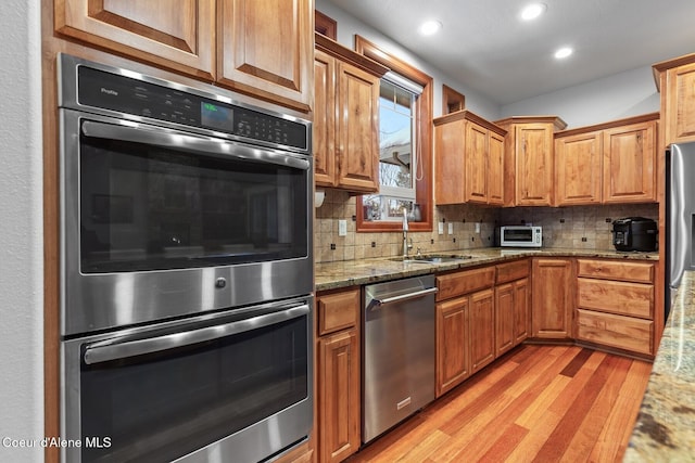 kitchen with light stone countertops, appliances with stainless steel finishes, sink, and decorative backsplash