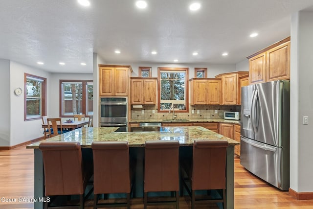 kitchen featuring stainless steel appliances, a kitchen island, sink, and a kitchen bar