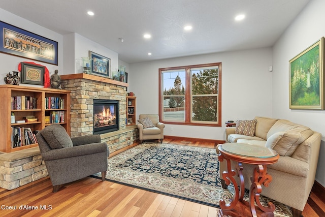 living room with wood-type flooring and a stone fireplace