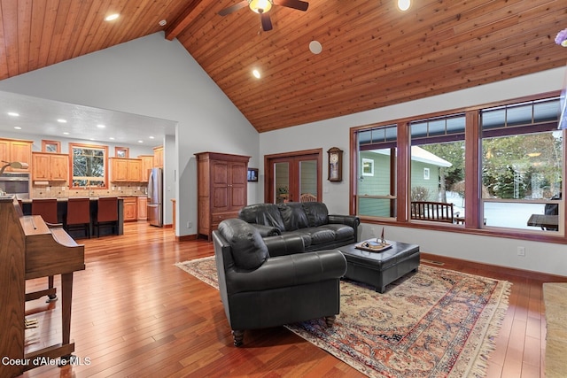 living room featuring ceiling fan, high vaulted ceiling, light hardwood / wood-style floors, wooden ceiling, and beamed ceiling