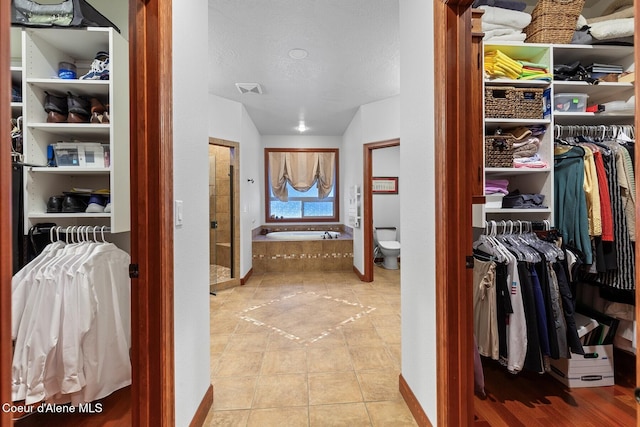 bathroom featuring toilet, tile patterned flooring, a textured ceiling, and a washtub