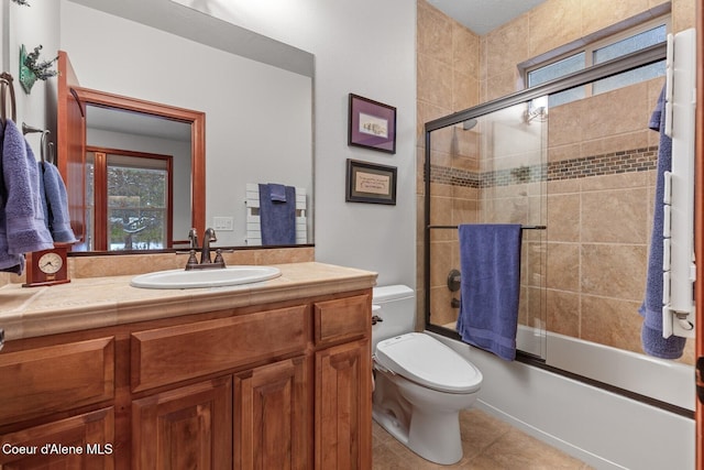 full bathroom with vanity, tile patterned flooring, bath / shower combo with glass door, and toilet