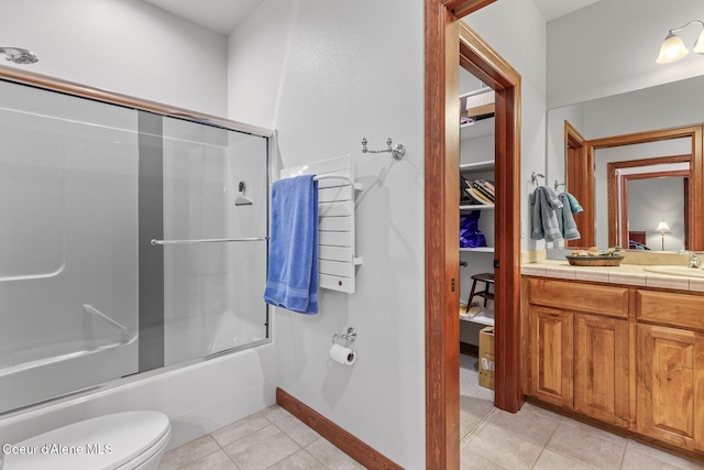 full bathroom with tile patterned flooring, bath / shower combo with glass door, vanity, and toilet