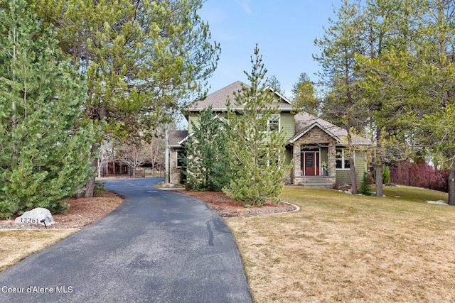 view of front of property with a front yard, stone siding, and driveway