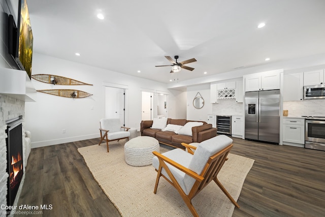 living room featuring dark wood-type flooring, indoor bar, beverage cooler, and ceiling fan