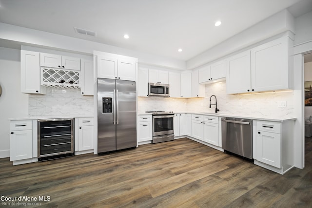 kitchen featuring white cabinetry, appliances with stainless steel finishes, and beverage cooler