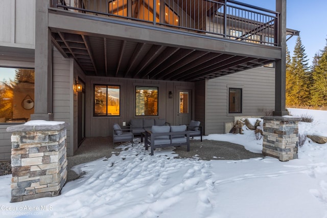 snow covered patio featuring a balcony and an outdoor hangout area