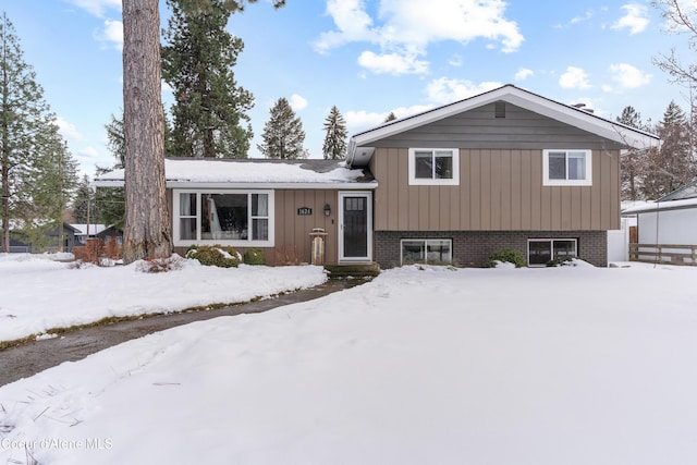 tri-level home featuring board and batten siding, brick siding, and a garage