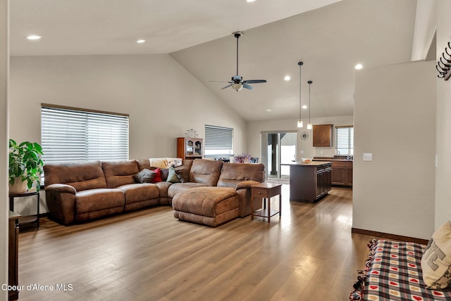 living room with light wood-type flooring, ceiling fan, high vaulted ceiling, and recessed lighting