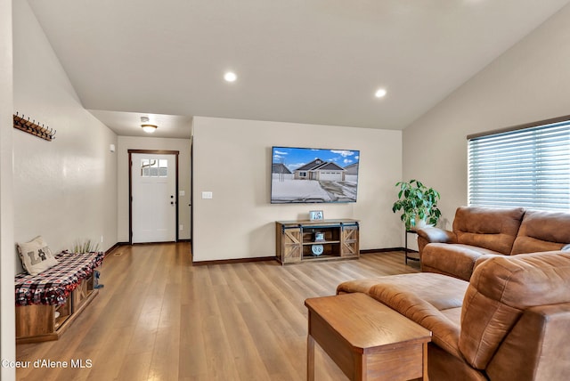 living room featuring light wood-type flooring, baseboards, and vaulted ceiling