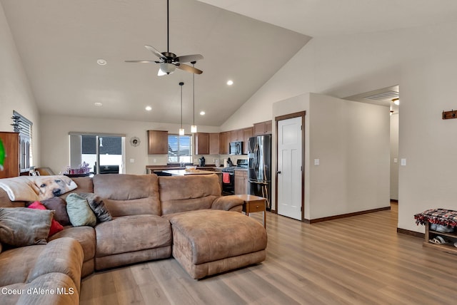 living area featuring high vaulted ceiling, light wood finished floors, recessed lighting, and baseboards