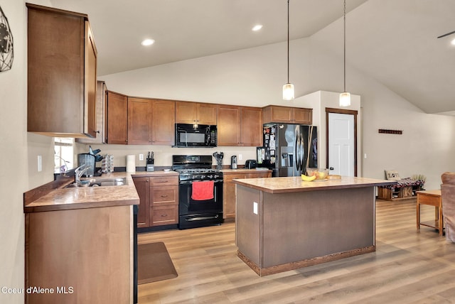 kitchen with black appliances, a kitchen island, light wood-style flooring, and pendant lighting