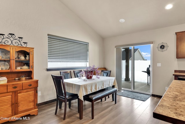 dining area with light wood-style floors, vaulted ceiling, and a wealth of natural light