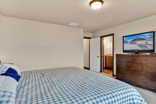 bedroom with connected bathroom and light colored carpet