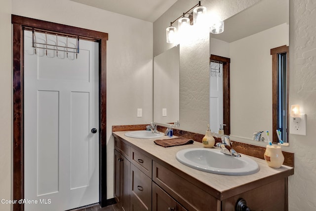 bathroom featuring a textured wall, a sink, and double vanity