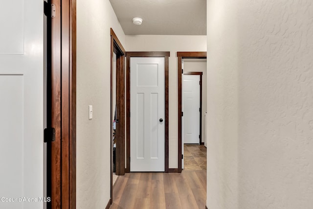 corridor with a textured wall and wood finished floors