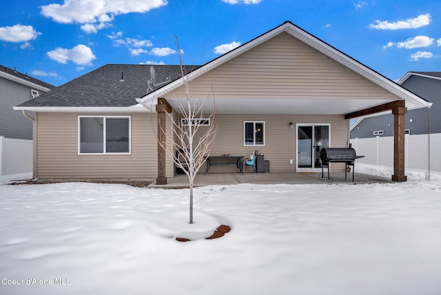 snow covered rear of property with a patio area and fence