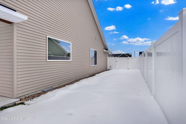 snow covered property featuring fence and a gate