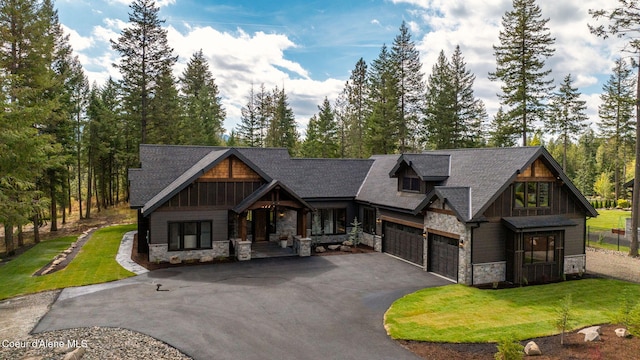 view of front of house with driveway, stone siding, an attached garage, and a front yard