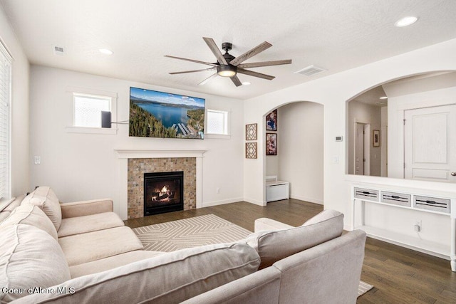 living room with dark hardwood / wood-style flooring, a fireplace, and ceiling fan