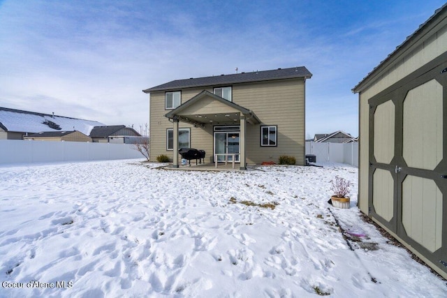 snow covered house featuring a storage unit