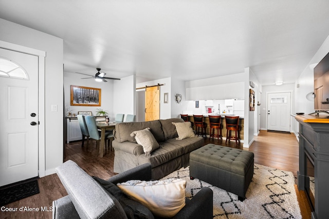 living room featuring ceiling fan, wood-type flooring, and a barn door