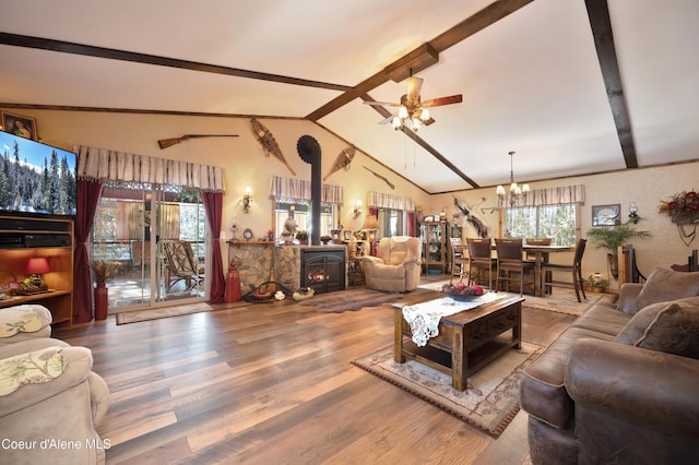 living room featuring hardwood / wood-style flooring, lofted ceiling, a wood stove, and ceiling fan with notable chandelier