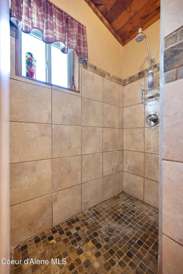 bathroom featuring a tile shower and wooden ceiling