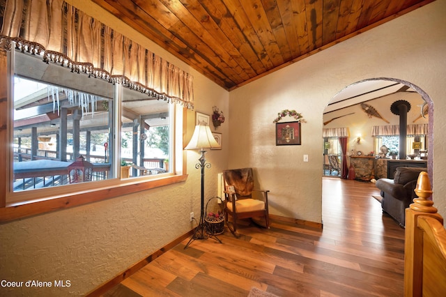 sitting room with wood ceiling, vaulted ceiling, a wood stove, ornamental molding, and hardwood / wood-style flooring