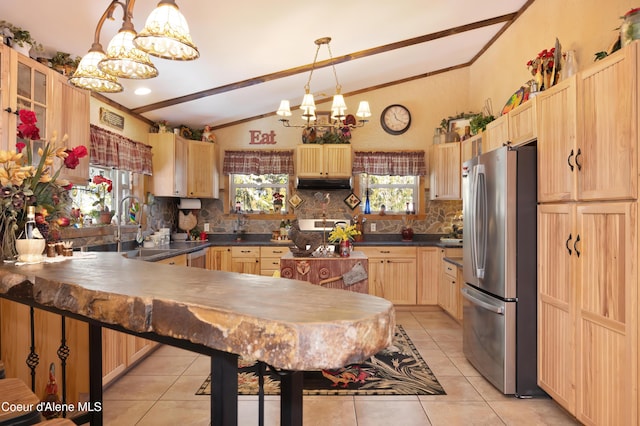 kitchen featuring light tile patterned flooring, a chandelier, vaulted ceiling, hanging light fixtures, and stainless steel fridge