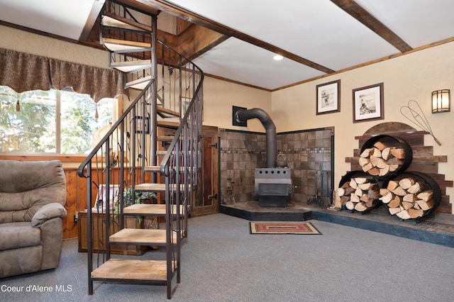 living room with beamed ceiling, carpet flooring, crown molding, and a wood stove