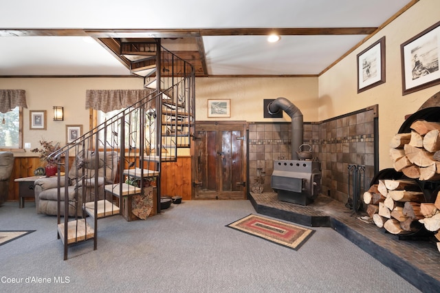 carpeted living room featuring crown molding, wood walls, and a wood stove