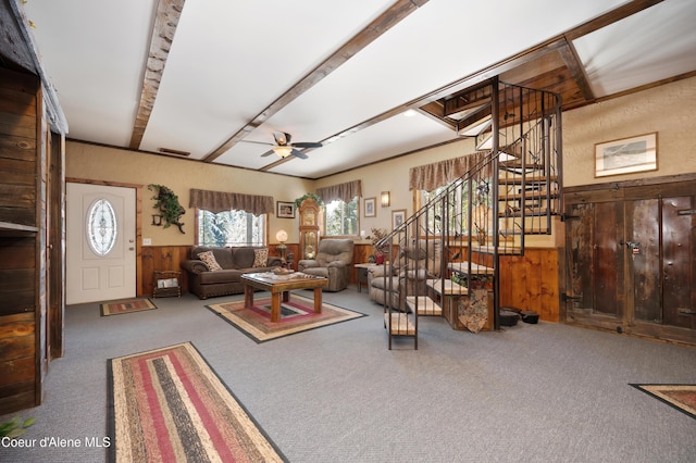 carpeted living room featuring ceiling fan and wood walls