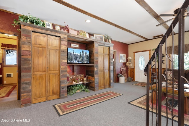 entryway featuring beamed ceiling, ceiling fan, and carpet floors