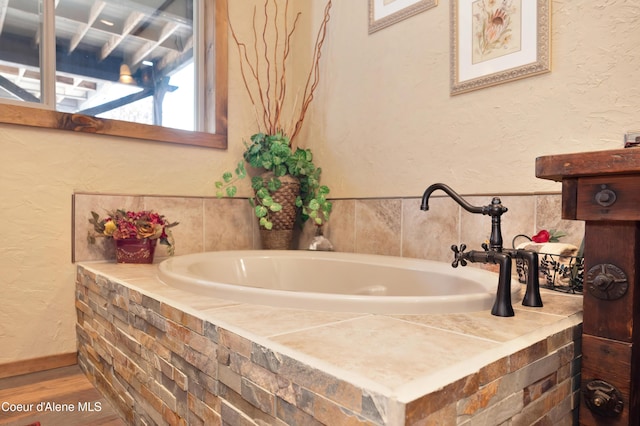 bathroom featuring hardwood / wood-style floors and tiled tub