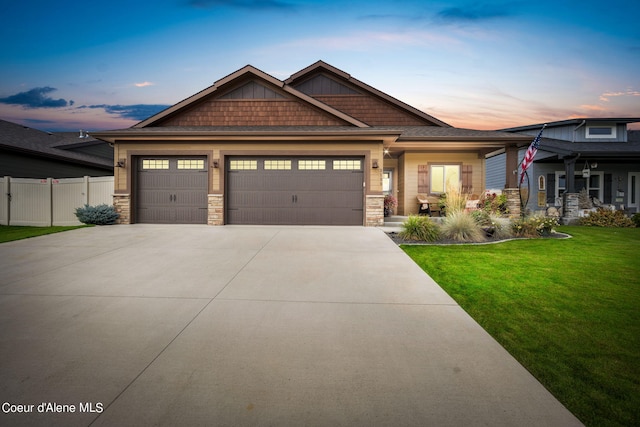 craftsman-style house with stone siding, a front lawn, an attached garage, and fence