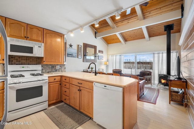 kitchen with vaulted ceiling with beams, light countertops, a sink, white appliances, and a peninsula