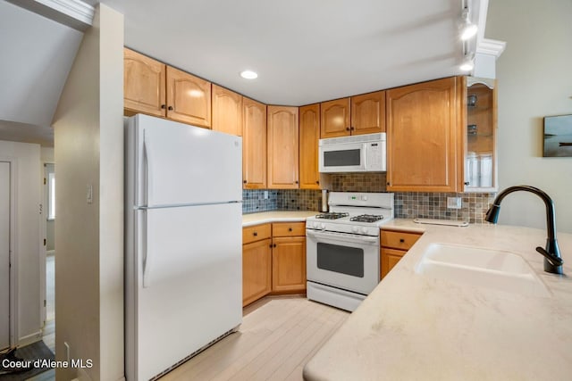 kitchen featuring white appliances, light wood-style flooring, a sink, light countertops, and backsplash