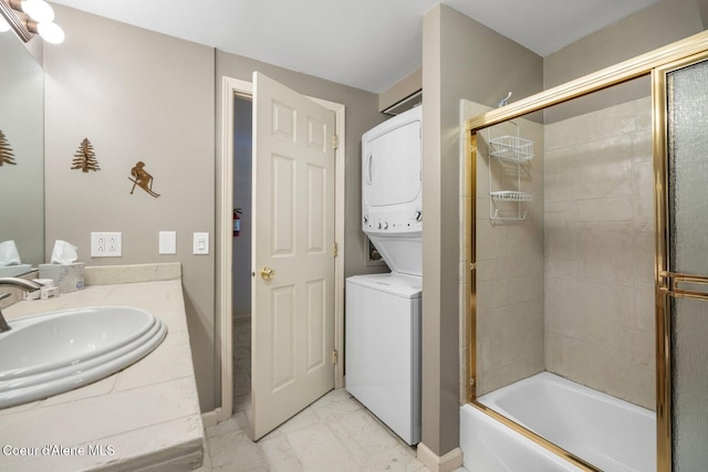 full bath featuring marble finish floor, shower / bath combination with glass door, vanity, and stacked washing maching and dryer