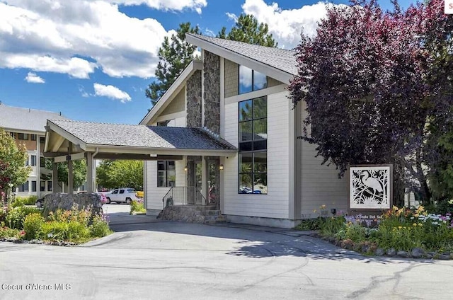 view of front of home with a carport, roof with shingles, and driveway